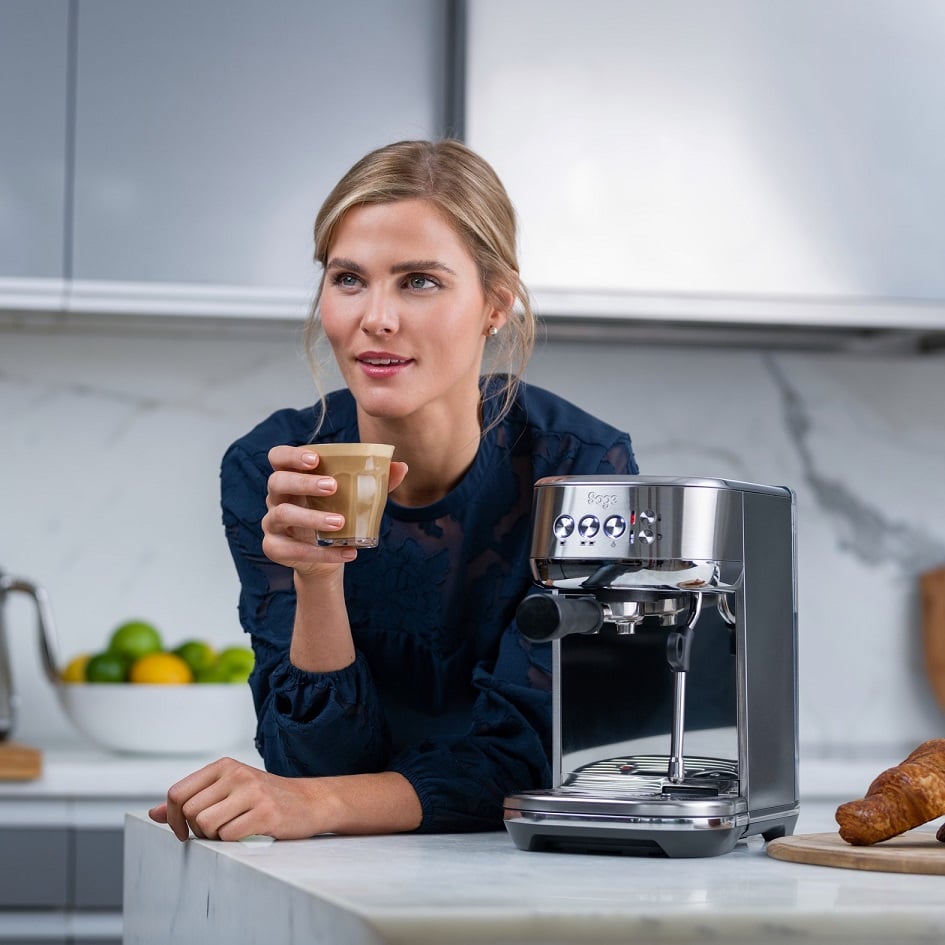 Frau, die Cappuccino trinkt, der mit einer Sage the Bambino Plus Siebträgermaschine zubereitet wurde